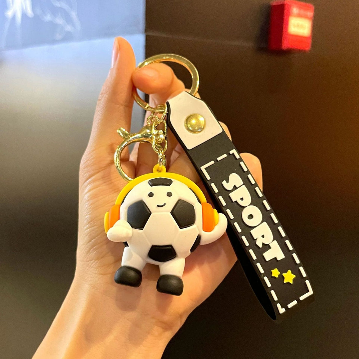 Breloc Flippy din acril negru, design minge de fotbal cu căști, detaliu cureluță prindere