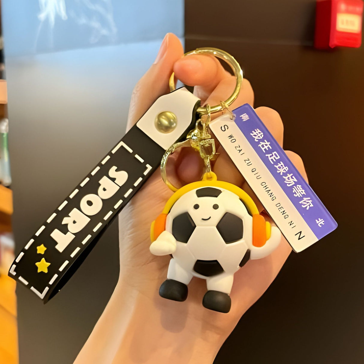 Detaliu breloc Flippy minge fotbal cu căști și mesaj decorativ imprimat, acril negru