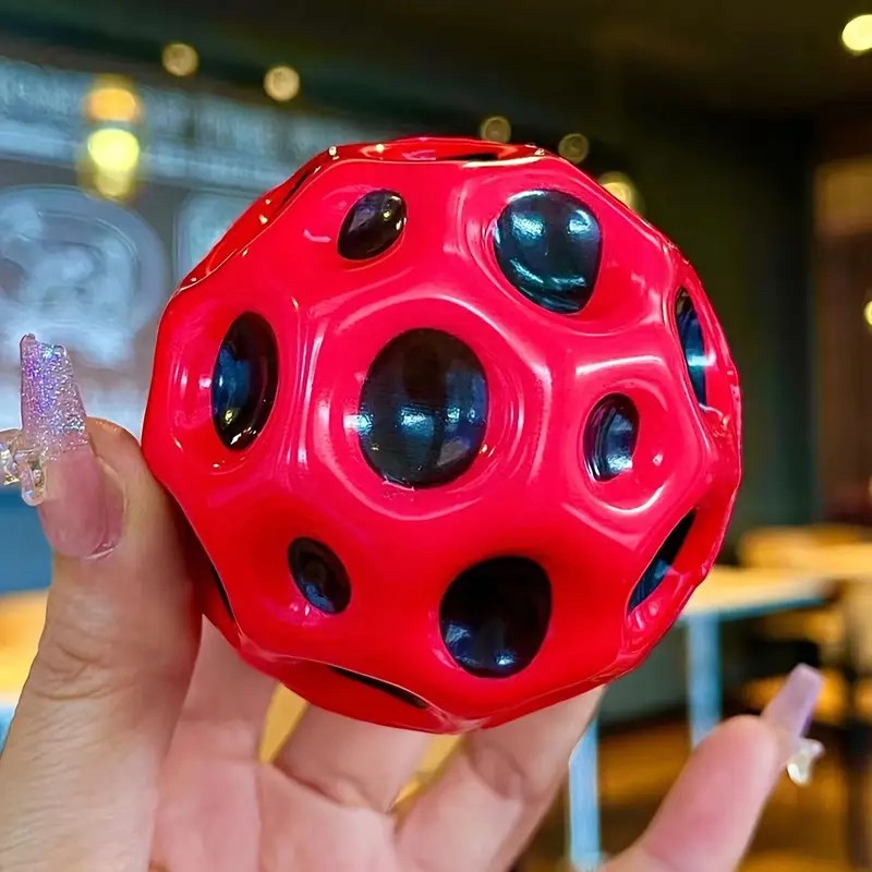 Minge Space Moon Ball roșie 66 mm ținută în mână, comparație dimensiune și culoare