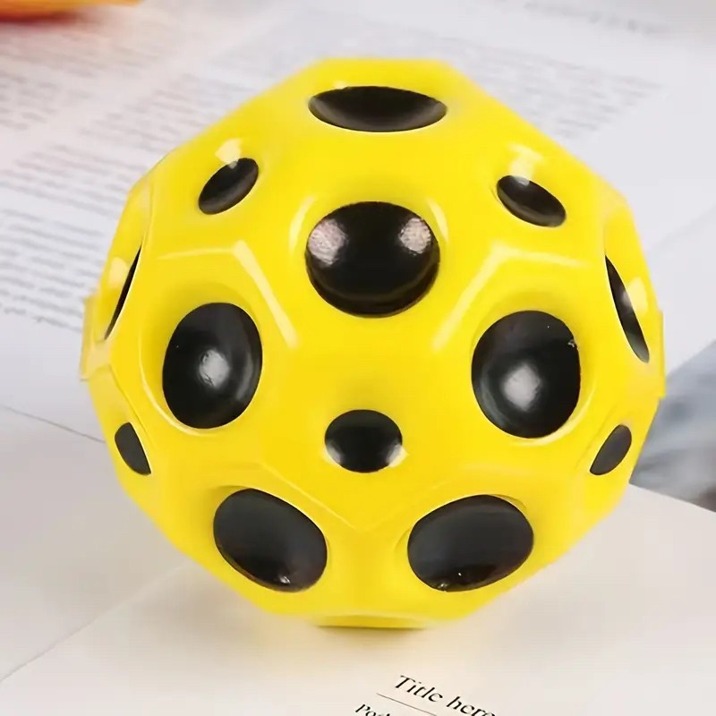 Minge hiperelastică galbenă 66 mm Space Moon Ball ținută în mână, perspectivă laterală